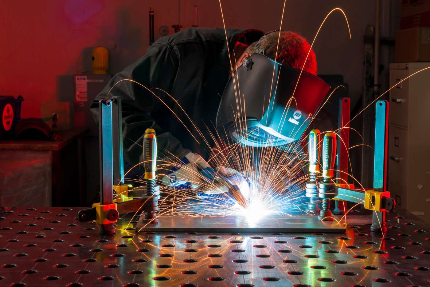 Sparks leave colorful glowing trails as a welder seams two piece of metal together.
