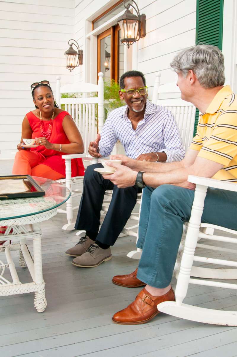 Frieds gather for beverages and food on an antebellum porch.