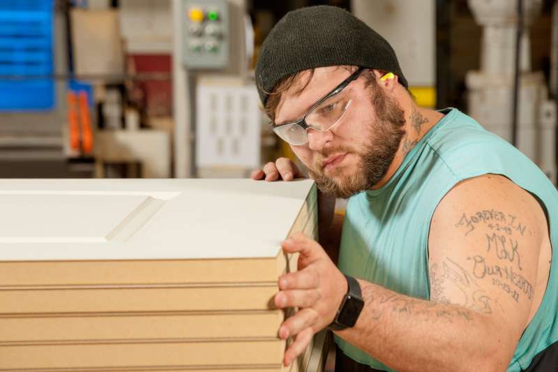 A door manufacturing employee closely inspects products to ensure quality standards are met.