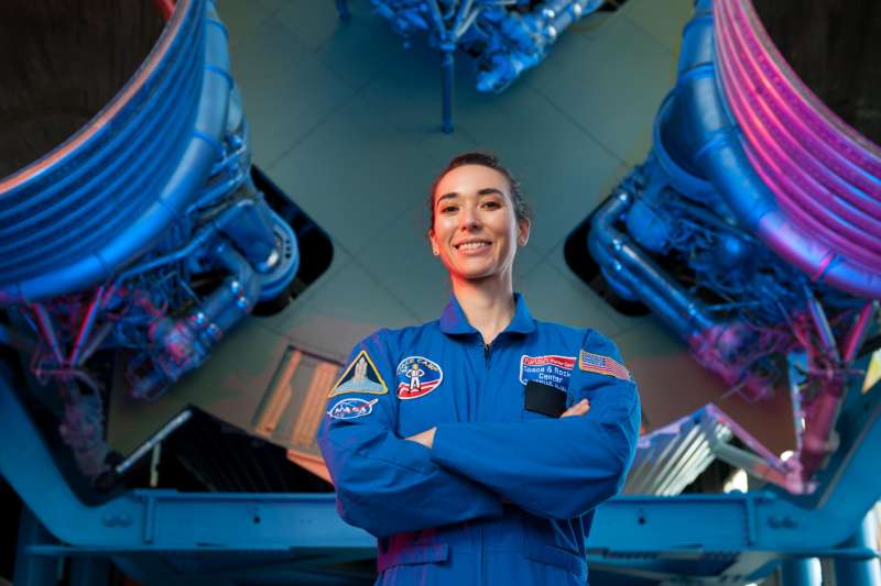 Performer and astronaut trainder Lain Velasco stands uniformed in front of the Saturn V boosters at the U.S. Space and Rocket Center in Hutnsville.