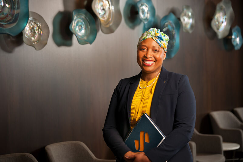 Headshot for a bank executive showing the subject smiling in a conference room holding a company branded notebook.