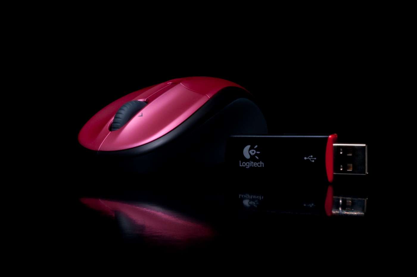 Electronics hero product photography of a wireless mouse and USB stick photographed on a glossy black background.
