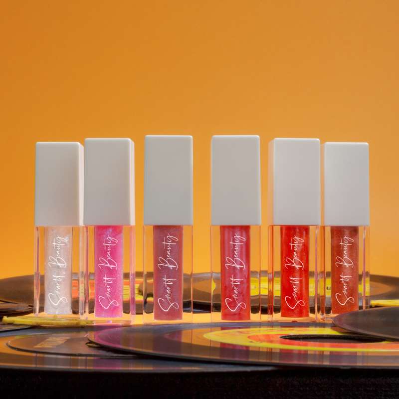 6 individiual lip gloss tubes are shown standing on a pile of 45 rpm recirds.